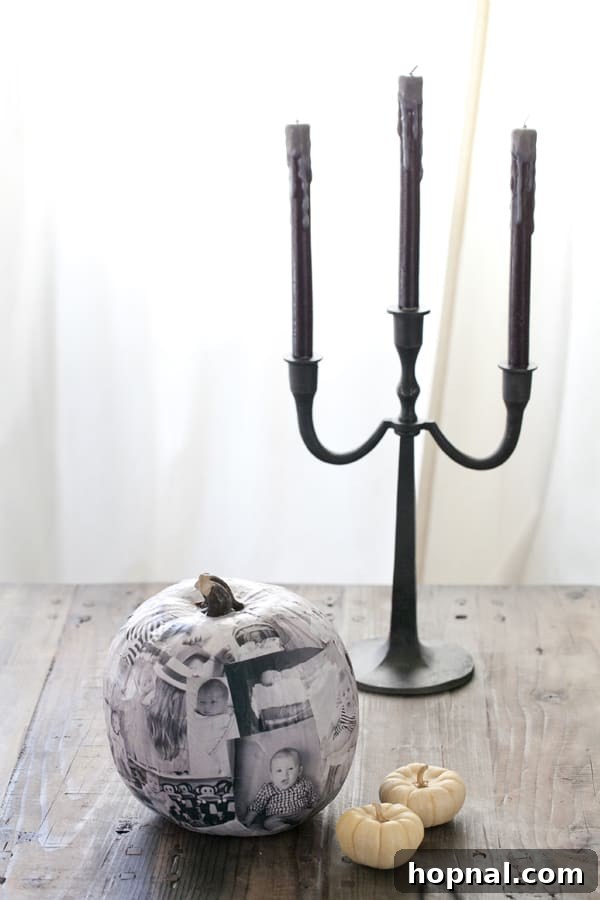 A decoupage pumpkin decorated with black and white photos of a baby, creating a personalized Halloween decoration.