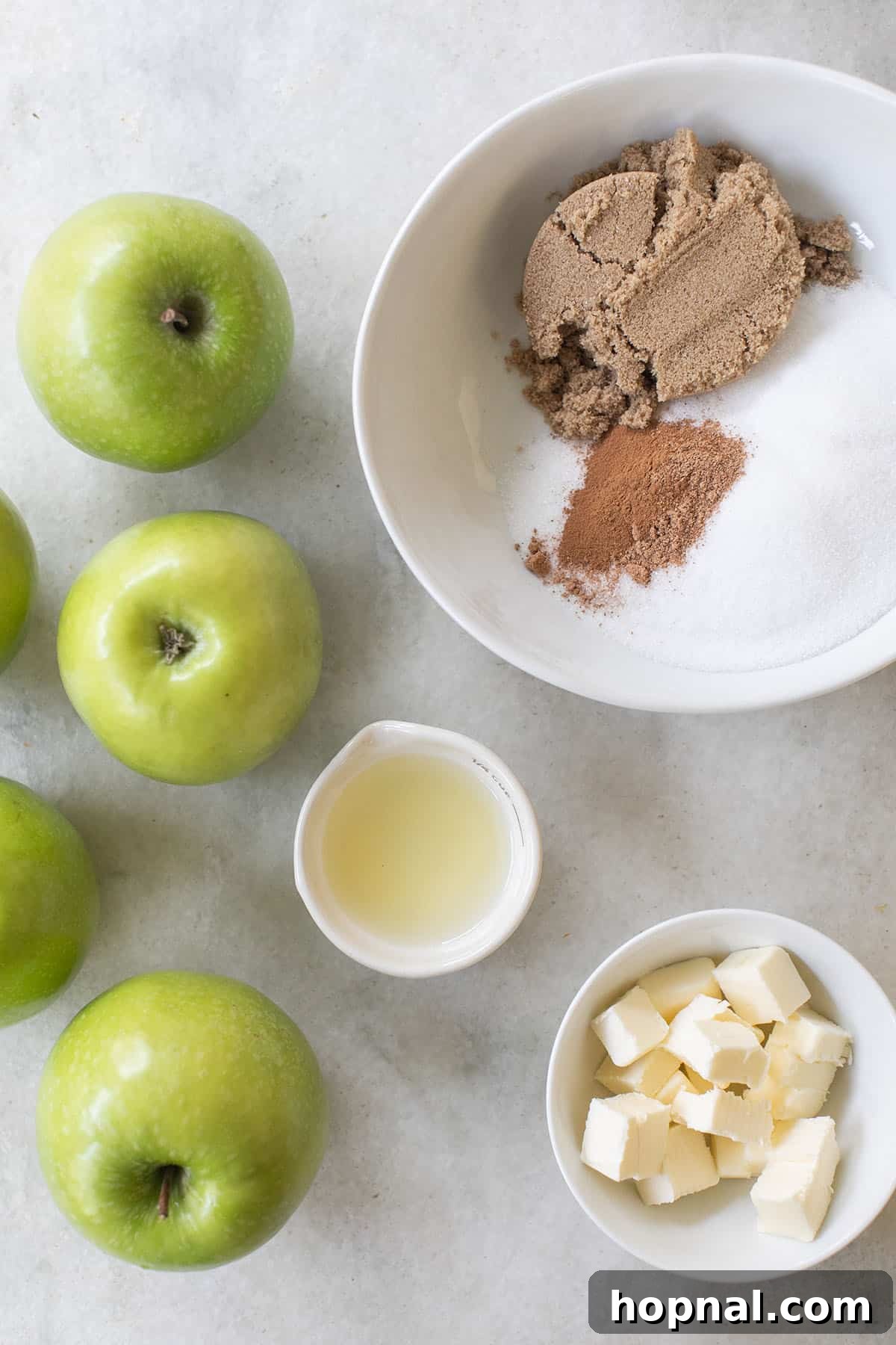 Fresh apples, lemon juice, aromatic spices, sugar, and butter prepared in bowls for the pie filling