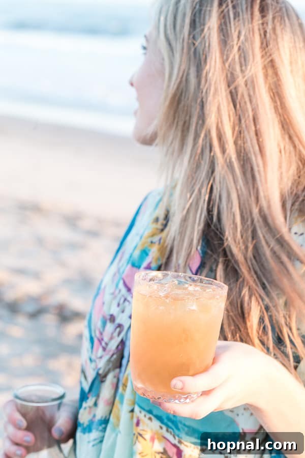 Crafting Your Dream Beach Bonfire Night 10 Woman holding a refreshing drink by the beach bonfire, enjoying the evening.