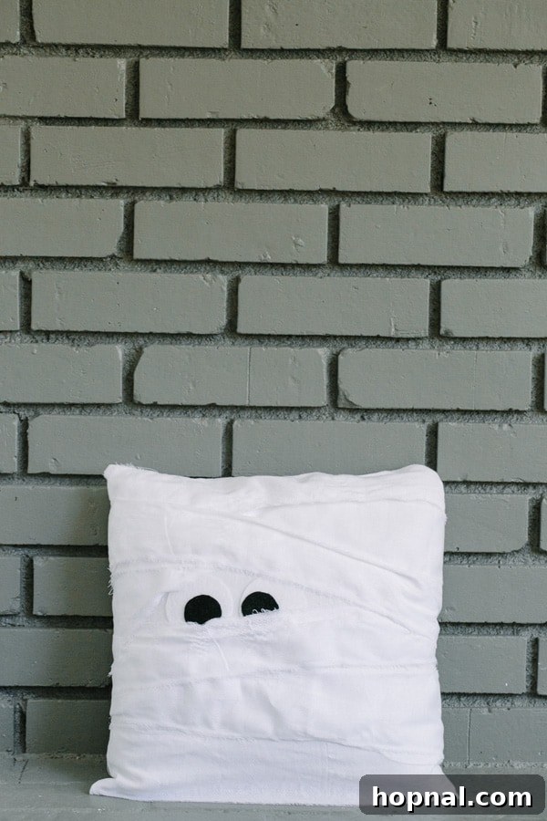 Close-up of a completed mummy pillow, highlighting the textured fabric strips and googly eyes