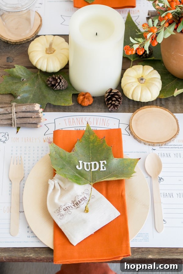 Little Gobblers' Thanksgiving Table 4 A close-up of a kids' Thanksgiving table setting featuring a giant leaf with letter stickers for a name card, pumpkins, crayons, and bamboo dinnerware.