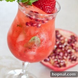 A delicious Strawberry Pomegranate Mojito, garnished with mint and fruit.