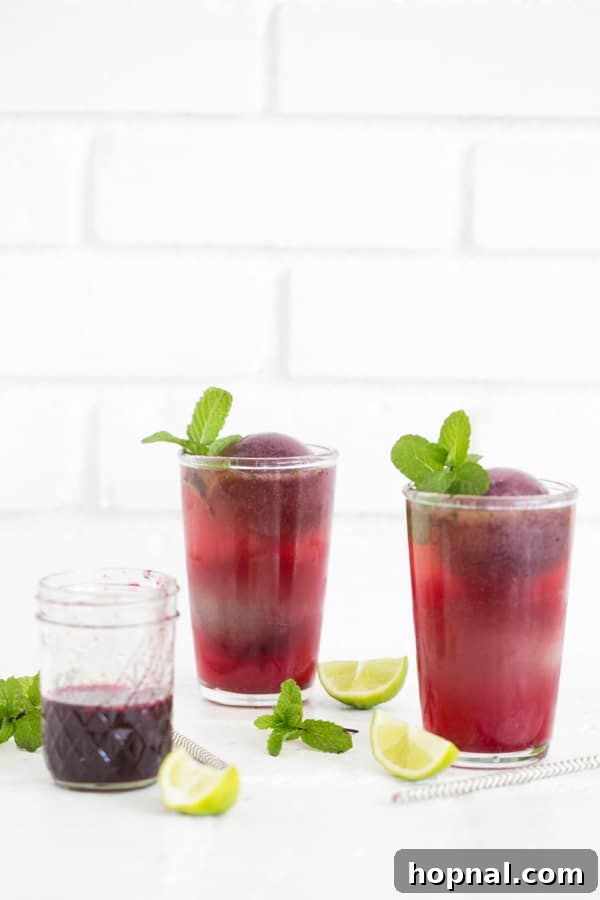 Two blueberry mojitos side-by-side, showcasing their beautiful blue hue and fresh mint garnish.