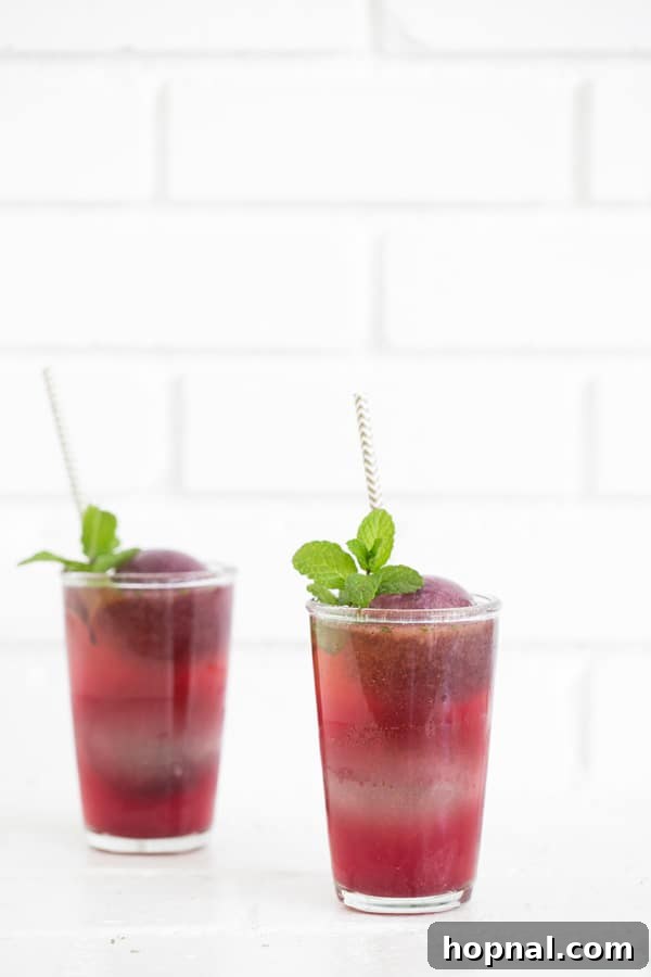 A hand holding a glass of blueberry mojito, highlighting the vibrant colors and appealing presentation.