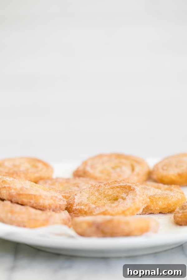 Homemade churros arranged on a plate, generously coated in cinnamon and sugar, ready to be enjoyed.