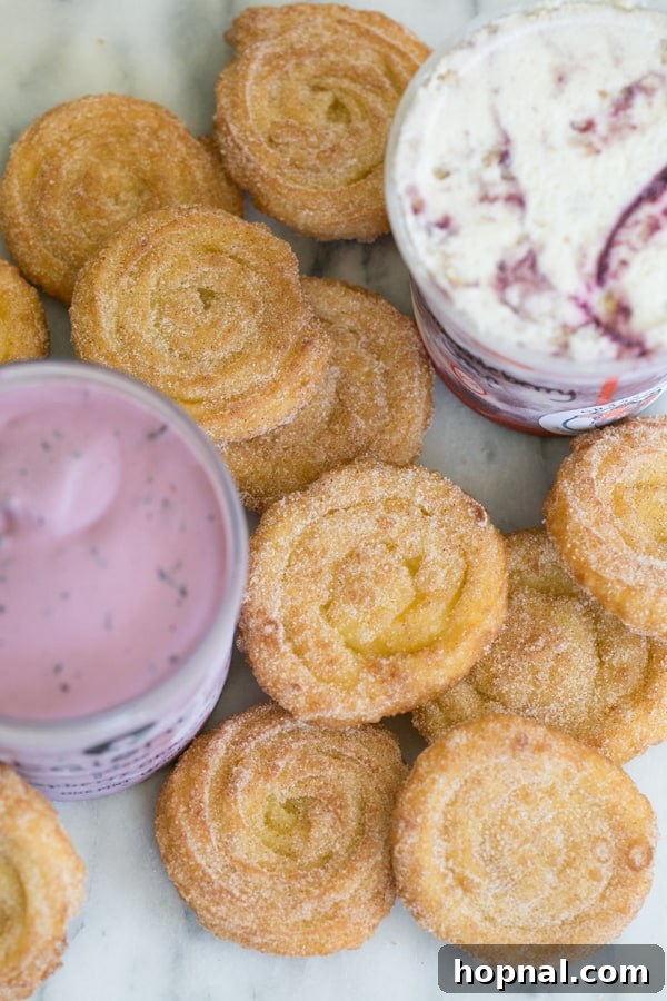 A vibrant scene of homemade churros on a marble table, accompanied by various tubs of ice cream, hinting at customization possibilities.