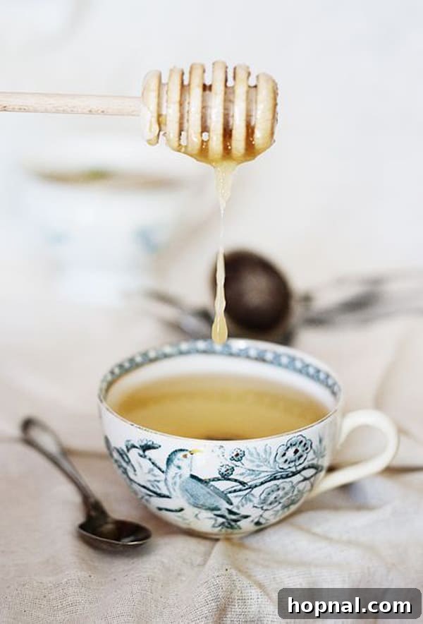 Golden honey gracefully drizzling into a freshly brewed cup of hot tea.