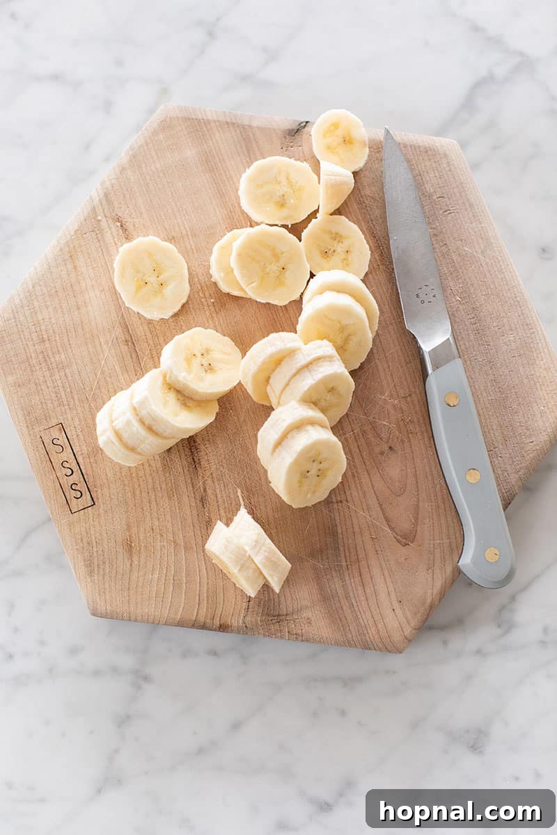 Heavenly Banana Pudding 10 Slices of fresh banana neatly arranged on a cutting board, ready to be layered into the banana pudding.