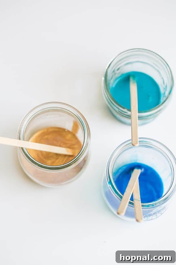 Blue, gold, and turquoise paint in jars with wooden stir sticks