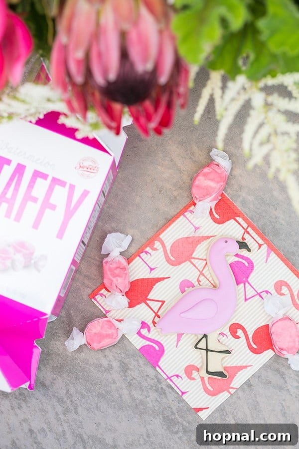 A display of flamingo pool party desserts including a flamingo sugar cookie, taffy, and striped napkin