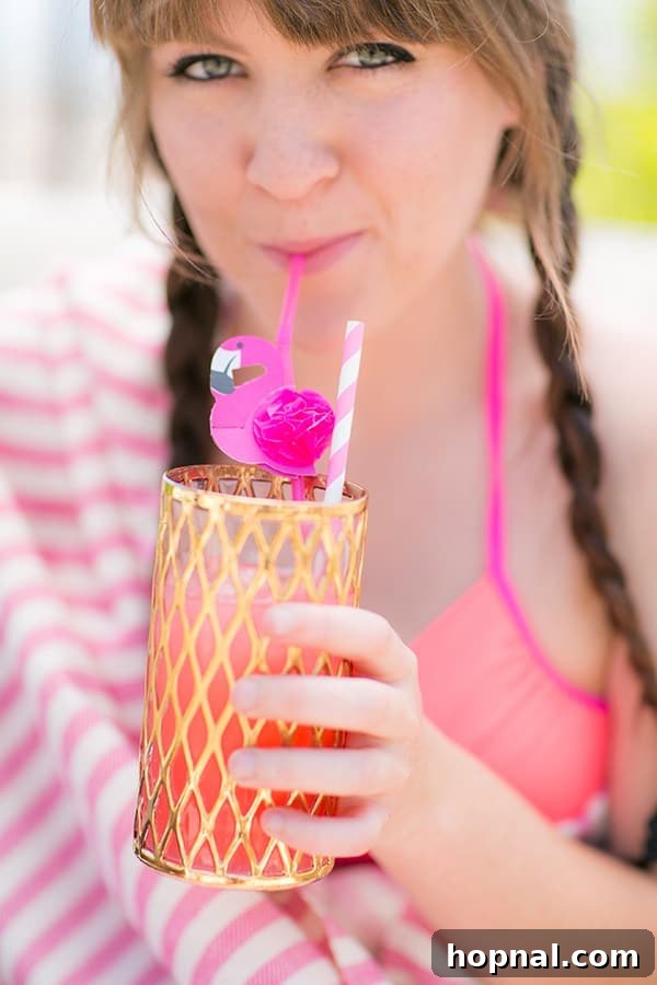Girl sipping a cocktail out of a flamingo straw at a flamingo pool party, enjoying the festive atmosphere