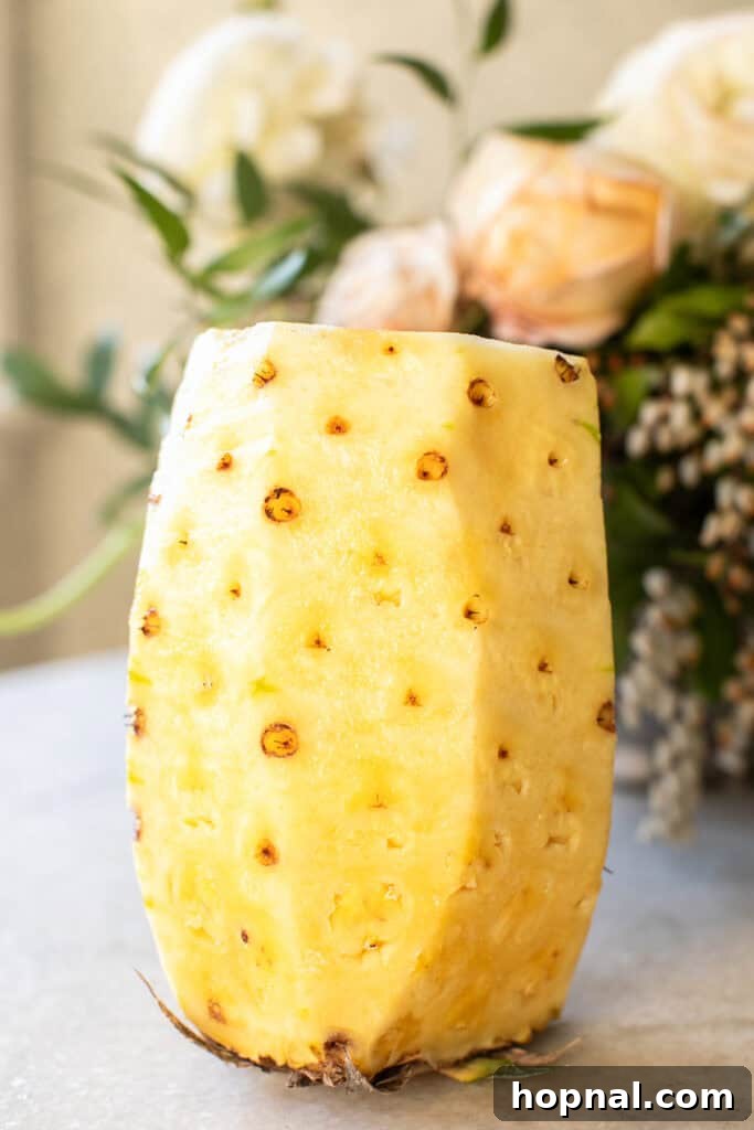 The outer rind of the pineapple expertly removed, revealing the golden flesh beneath.