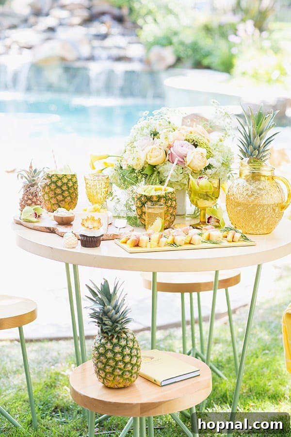 An elaborate pineapple party setup with an abundance of food and drinks, beautifully arranged on a wooden table beside a shimmering pool.
