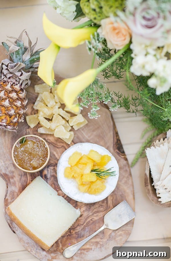 An artfully arranged pineapple cheese plate featuring dried pineapple, fresh baby pineapple, and various cheeses.