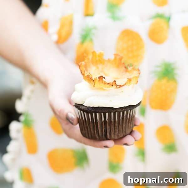 A hand gently holding a charming pineapple cupcake, showcasing its delightful design.