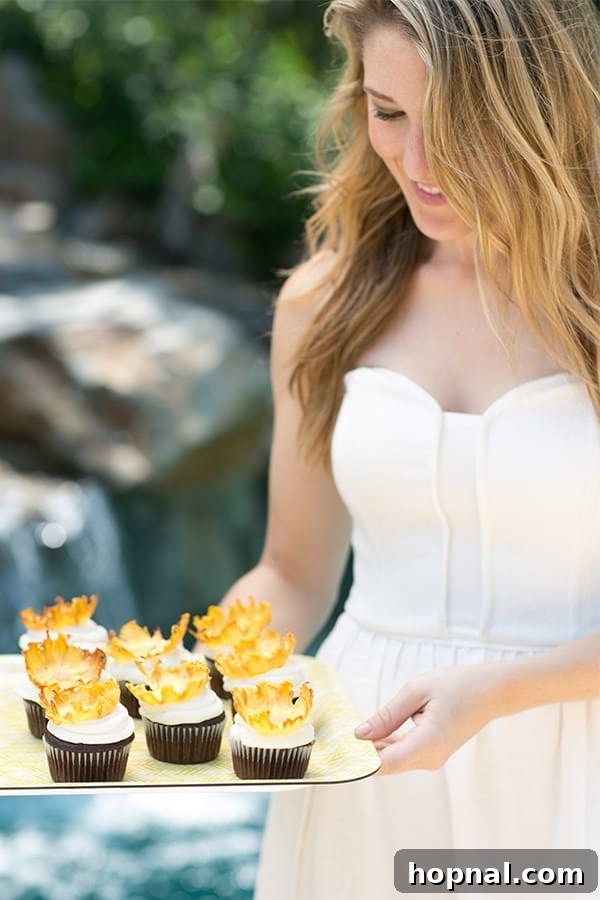 Eden Passante holding a yellow tray laden with an assortment of charming pineapple cupcakes.