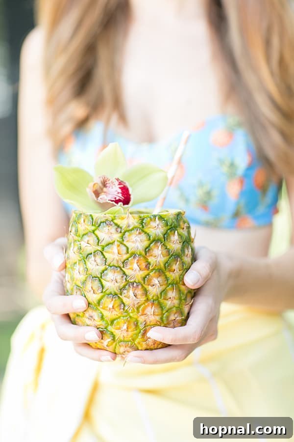 A person holding a beautifully garnished pineapple mojito cocktail, inviting a sense of tropical relaxation.