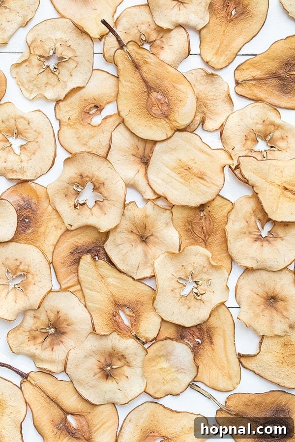 Perfectly golden and crispy homemade pear and apple chips arranged on a rustic wooden table, ready for delicious snacking.