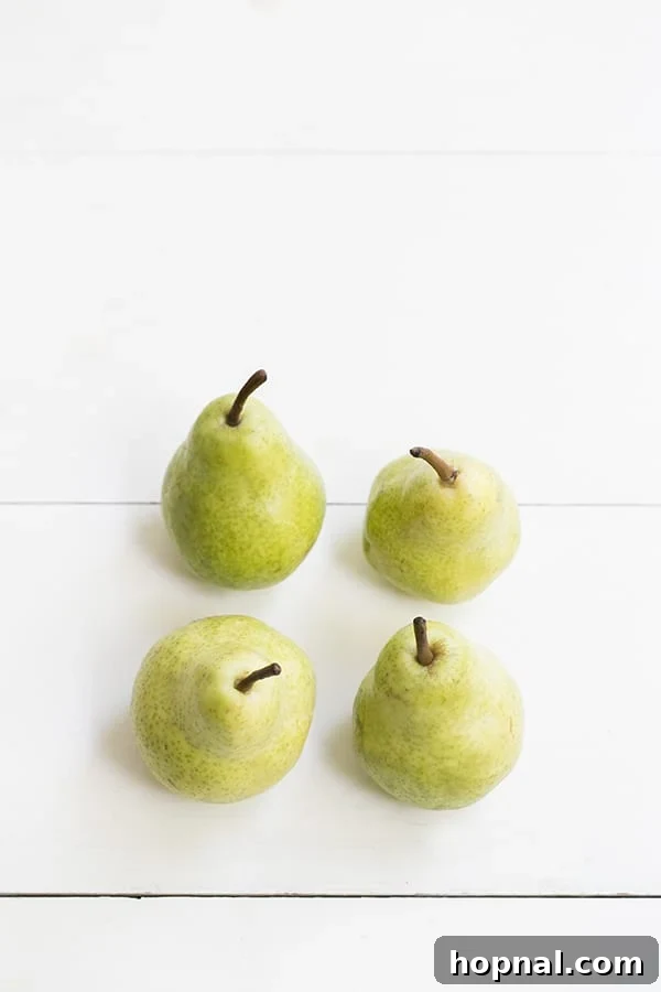 A selection of fresh, ripe pears neatly arranged on a rustic wooden surface, highlighting the quality of the primary ingredients.