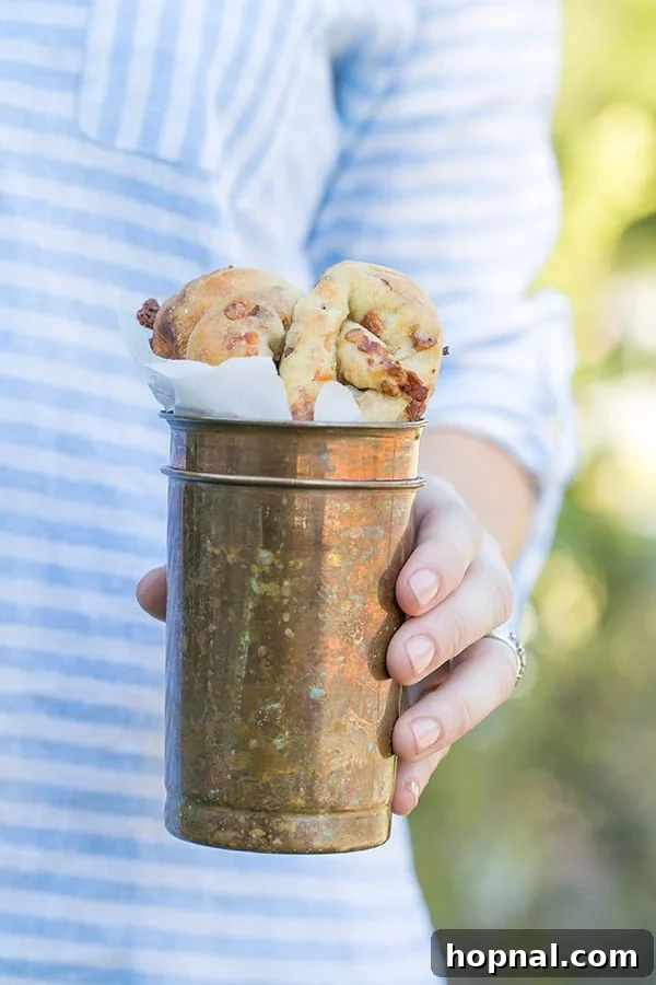 A close-up photograph of several freshly baked homemade bacon and cheese pretzels elegantly arranged within a stylish copper cup, inviting immediate enjoyment.