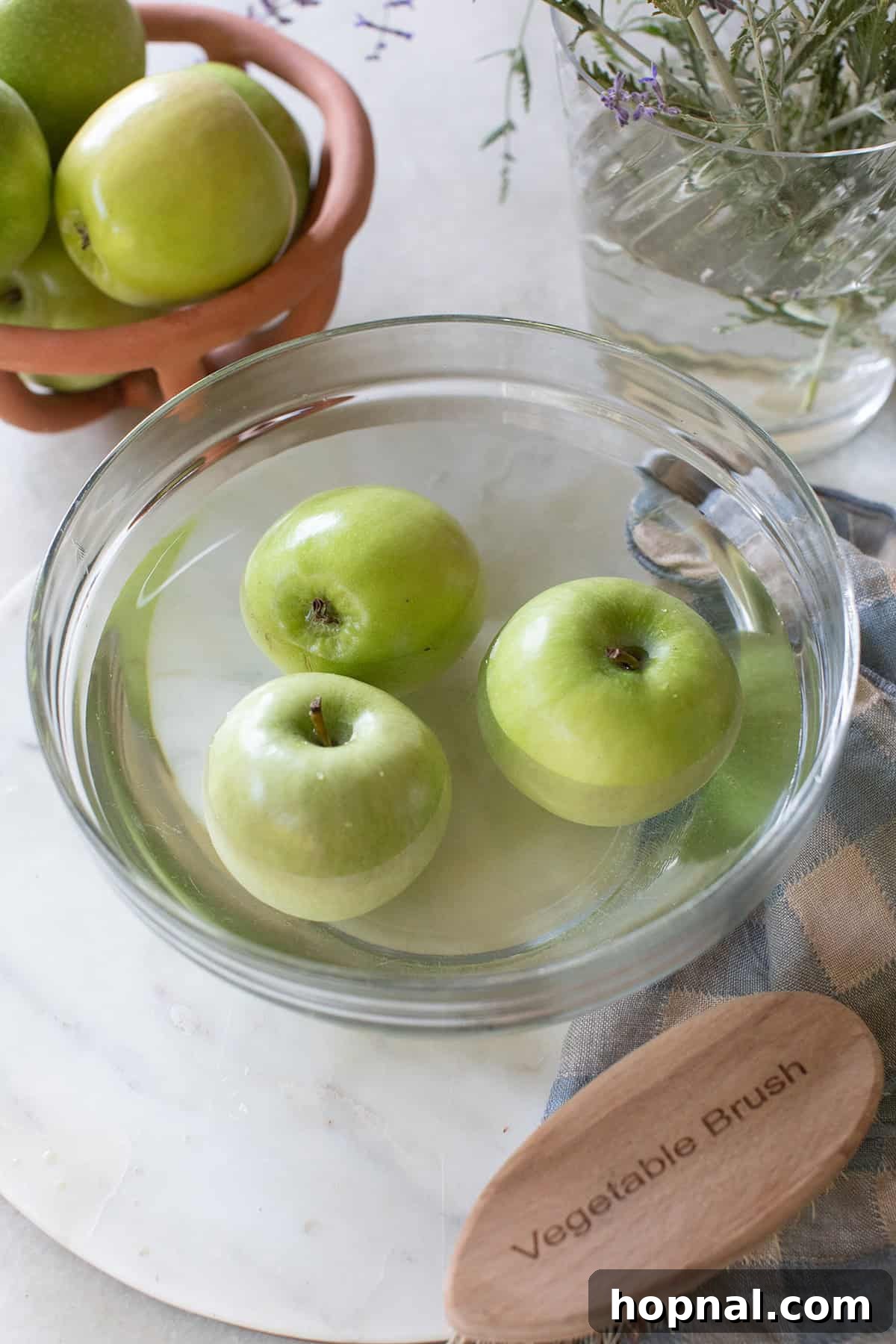 A close-up shot of an apple being meticulously scrubbed with a brush, illustrating the vital step of removing wax coating before making candy apples.