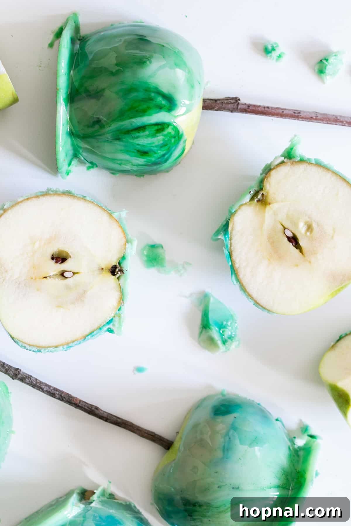 Two vibrant marbled candy apples, one presented whole and one meticulously cut in half to showcase its colorful interior and crisp texture.