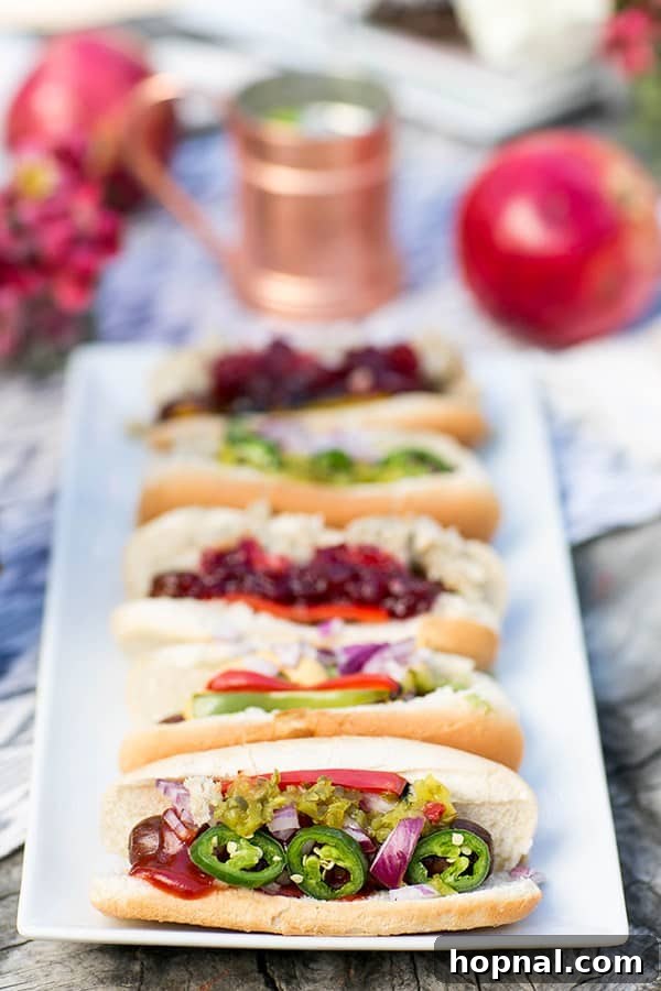 Gourmet hotdogs topped with various ingredients, cooking on a campfire grate during a Thanksgiving camping trip.