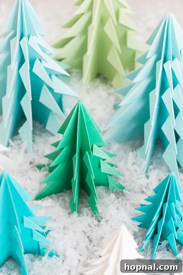 Paper origami trees on a table with fake snow. - Easy paper craft for festive Christmas decoration.