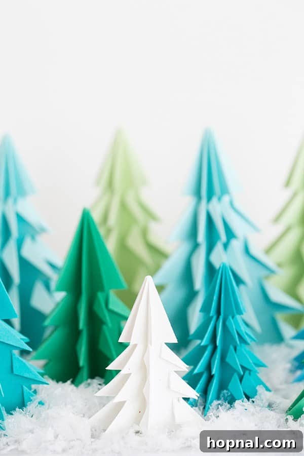Paper origami trees on a table with fake snow. - Essential materials for your DIY Christmas craft.