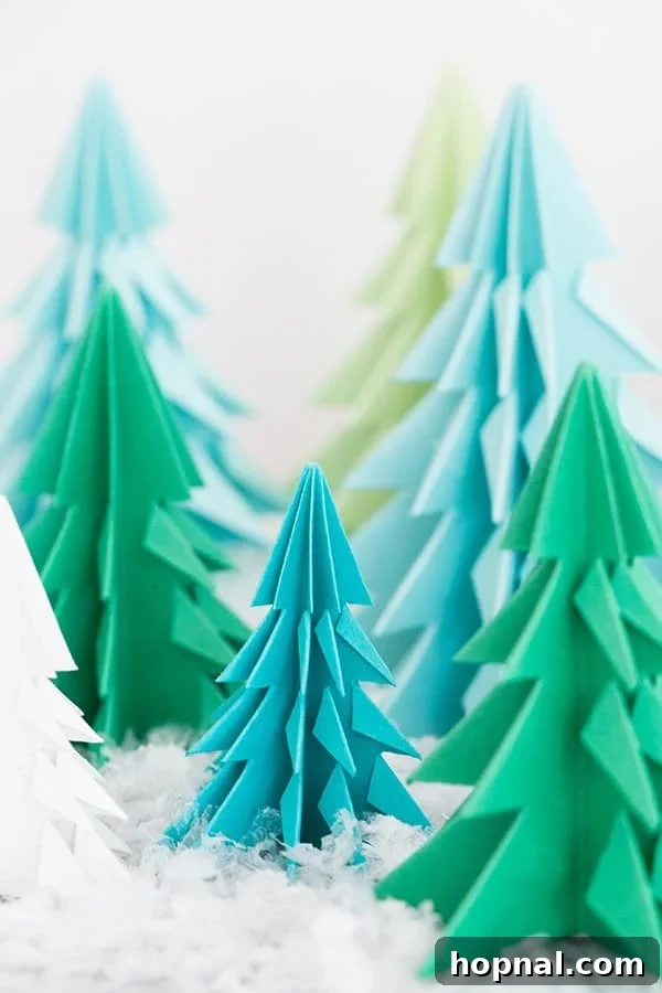 Paper origami trees on a table with fake snow. - A collection of beautiful paper Christmas trees.
