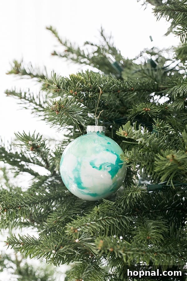 A single marble ornament elegantly hanging on a Christmas tree branch