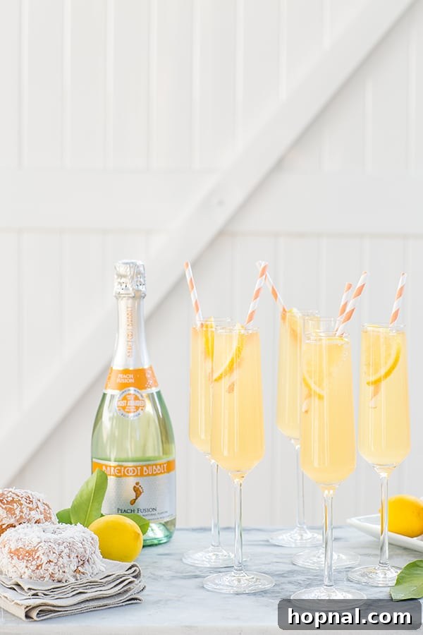 Side shot of sparkling wine bottles and multiple glasses filled with peach punch, ready to be served
