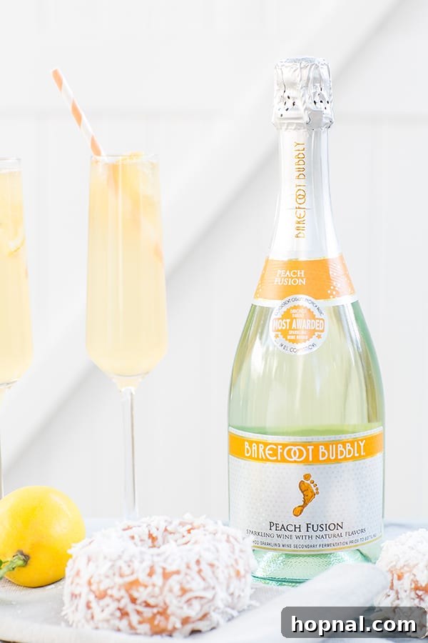 Close-up shot of a glass of peach punch with ice and garnishes, showcasing its vibrant color