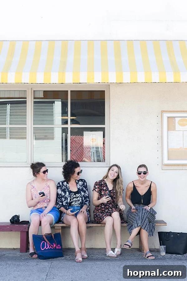 Four girlfriends sitting on a bench outside.