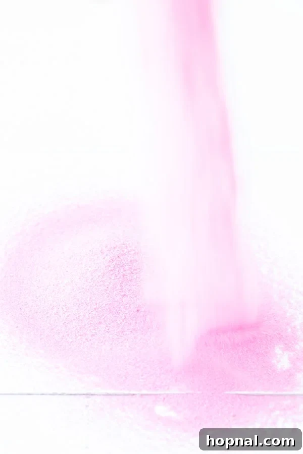 Close-up view of vibrant pink sand, ready for terrarium layering, suggesting a focus on colorful materials for the craft.