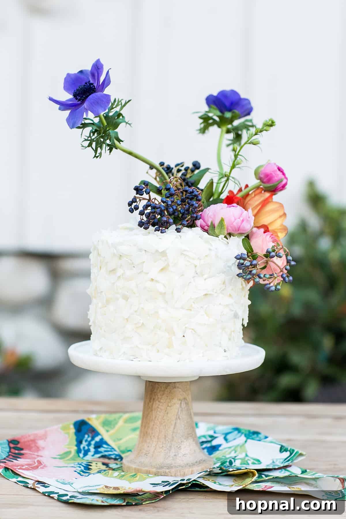 Easter party ideas for desserts with a beautifully decorated carrot cake, adorned with coconut flakes and flowers resembling bunny ears, perfect for a festive treat.