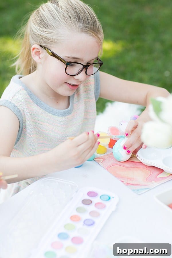 Dyeing for Easter Fun 18 A young girl intently painting an Easter egg with watercolors, fully focused on her creative and colorful design.