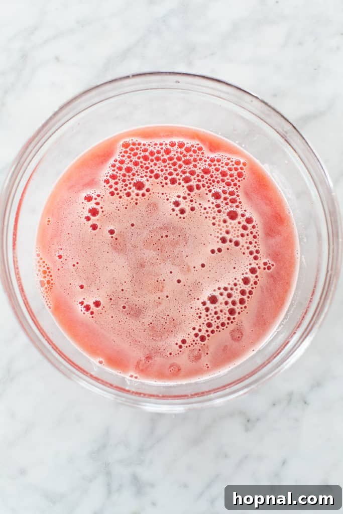 Cool Watermelon Quencher 7 A bowl filled with freshly strained watermelon juice, showing its smooth texture and vibrant red color.