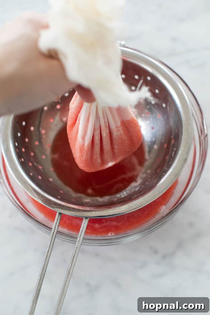 Cool Watermelon Quencher 8 Close-up of the straining process, with a spoon gently pressing the watermelon pulp in a cheesecloth-lined sieve to extract maximum juice.