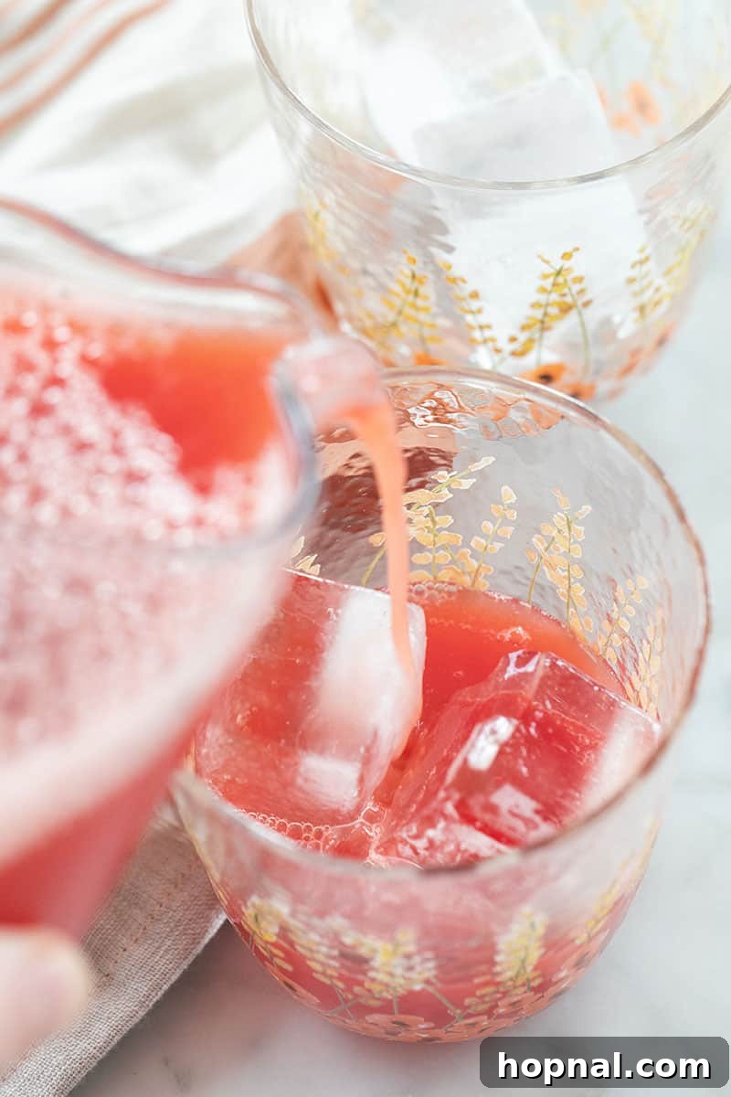 Cool Watermelon Quencher 9 Vibrant red watermelon juice being poured from a glass pitcher into a tall glass filled with ice, creating a refreshing cascade.