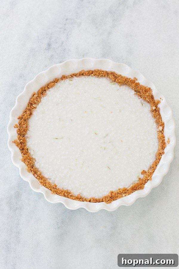 Zesty Island Dream Pie 3 A whole coconut key lime pie artfully arranged on a sleek marble table, showcasing its inviting golden crust and smooth, creamy filling.