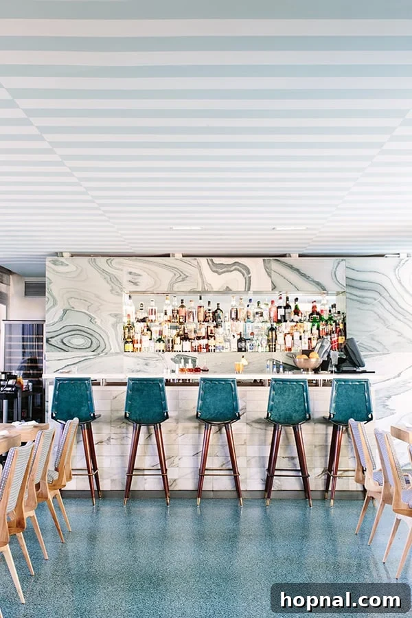The sophisticated bar at Viviane restaurant in Beverly Hills, featuring green velvet stools and marble countertops, a hallmark of Kelly Wearstler's design.