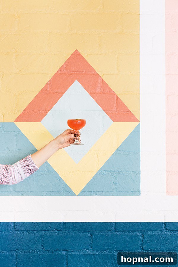 A guest holding a cocktail in front of a chic, colorful wall at Viviane, capturing the stylish social atmosphere.