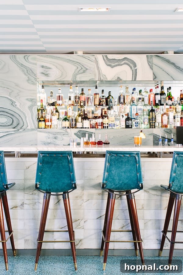 The elegant Viviane bar with its distinctive green chairs and marble top, showcasing Kelly Wearstler's interior design.