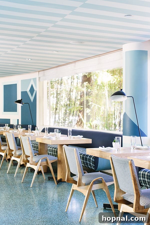 The stylish outdoor dining area at Viviane, featuring a blue and white striped ceiling and modern tables, perfect for al fresco dining in Beverly Hills.