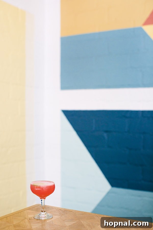 A beautifully presented cocktail in front of Viviane's colorful block wall, embodying the restaurant's vibrant style.