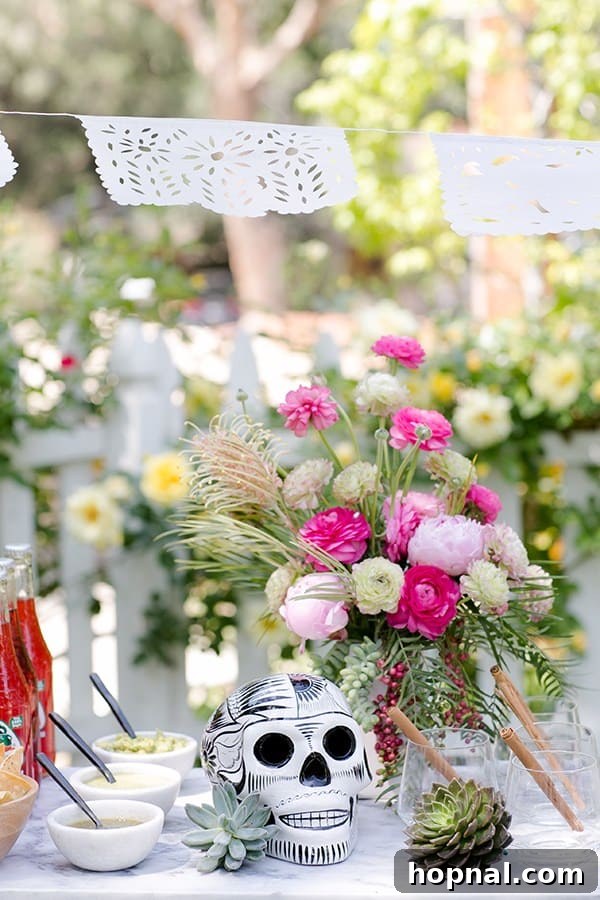 Spice Up Your Cinco de Mayo Celebration 18 Pink flower arrangements with a black and white skull and salsa on a marble table outside for a Cinco de Mayo party.