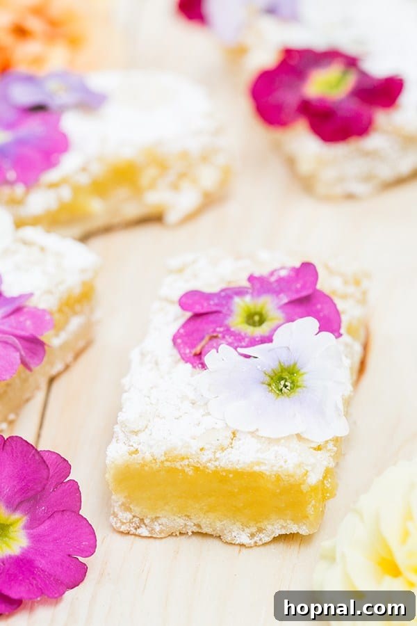 Perfectly baked lemon bars elegantly arranged and topped with an assortment of vibrant edible flowers.