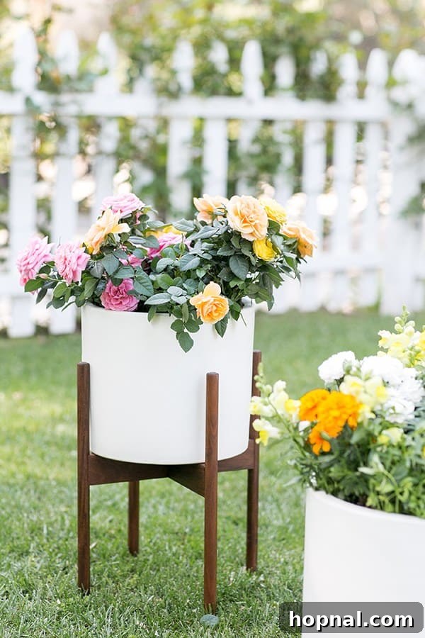 Elegant white pot filled with a colorful assortment of potted edible flowers, including delicate purple violas and pink blooms.