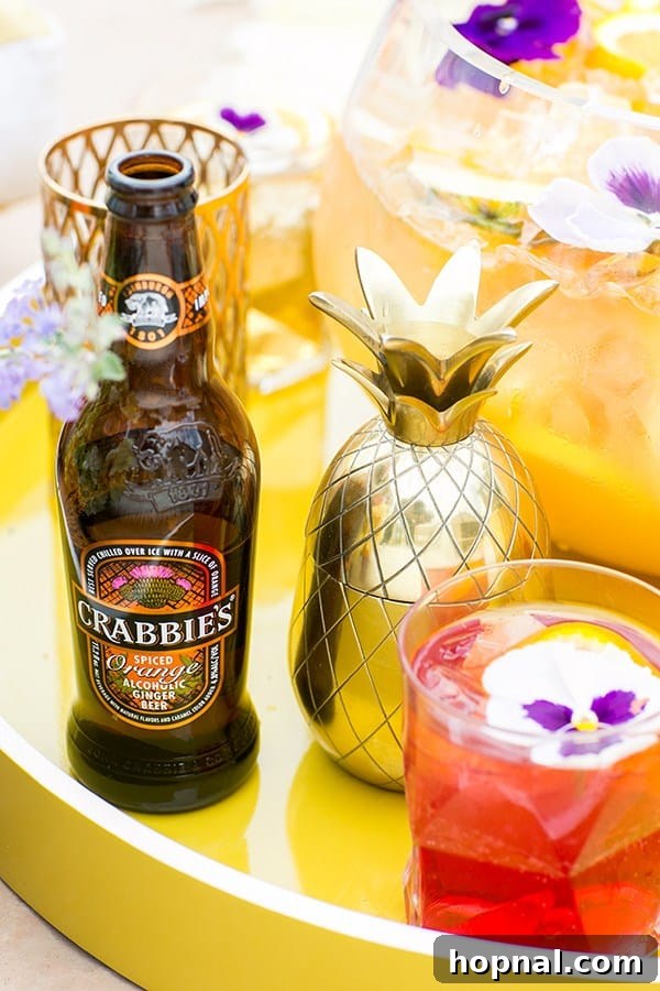 Crabbies ginger beer with a gold pineapple shaker and a cocktail on a yellow acrylic tray.